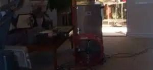 Dim indoor room with a red machine or cart near a bright doorway and cables on the floor