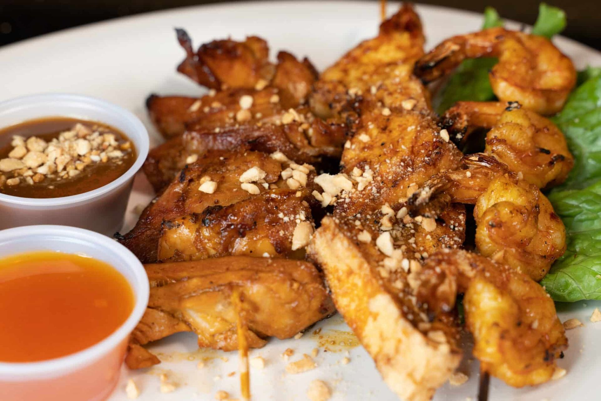 Plated fried chicken wings with two dipping sauces, topped with sesame seeds and herbs