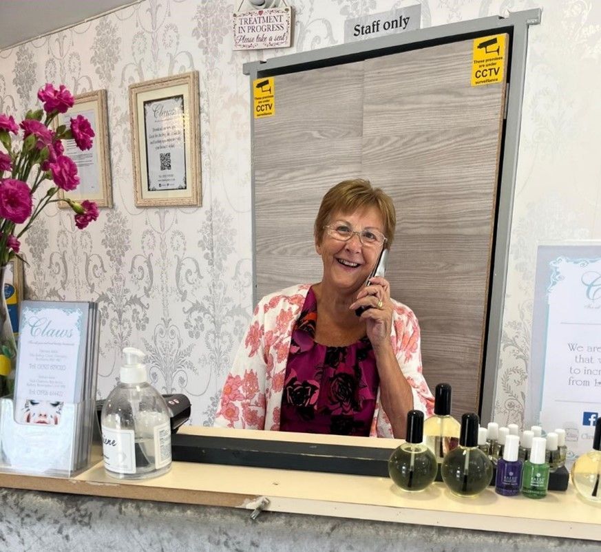Ann at Claws Nail and Beauty, smiling as she answers the phone at the reception desk