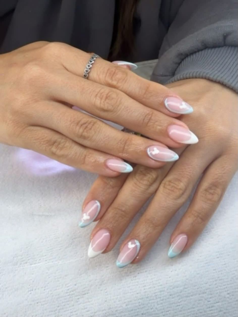 Almond nails with a soft pink base, white and pale blue French tips and tiny heart nail art at Claws Nail and Beauty