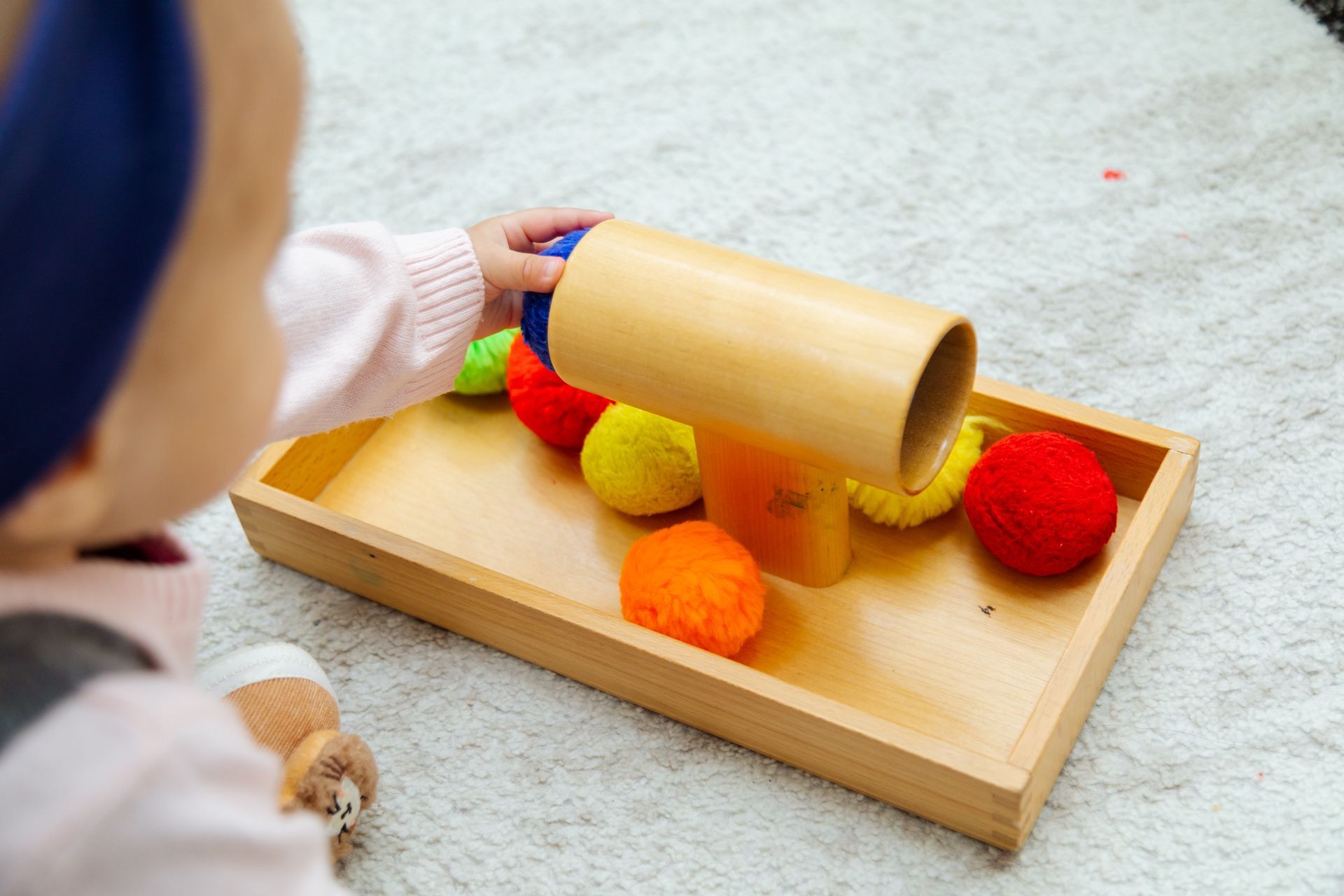 Close-up of a toddler playing with pompoms and a wooden toy. Close-up of a toddler playing with pompoms and a wooden toy.