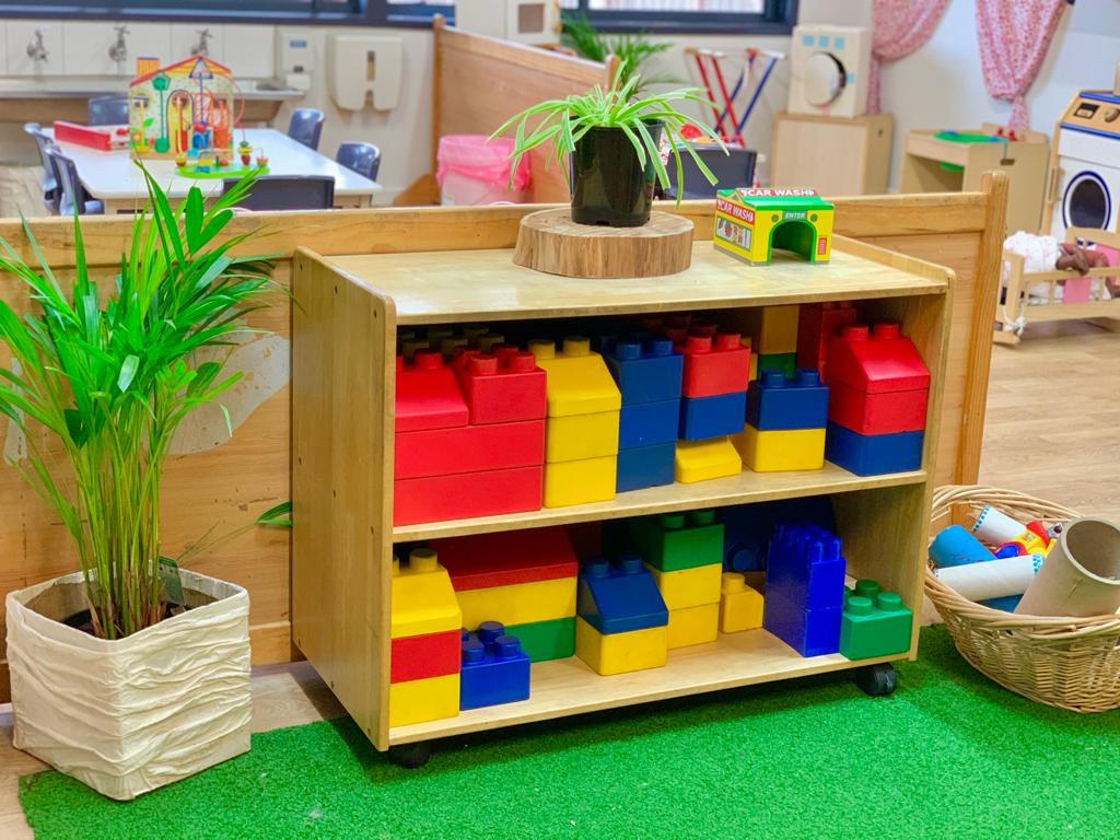 A vibrant play area featuring colourful toys and lush green plants.