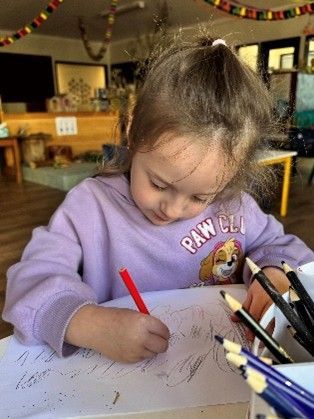 Close-up of a kid drawing on a colourful paper at a kindergarten. Close-up of a kid drawing on a colourful paper at a kindergarten.