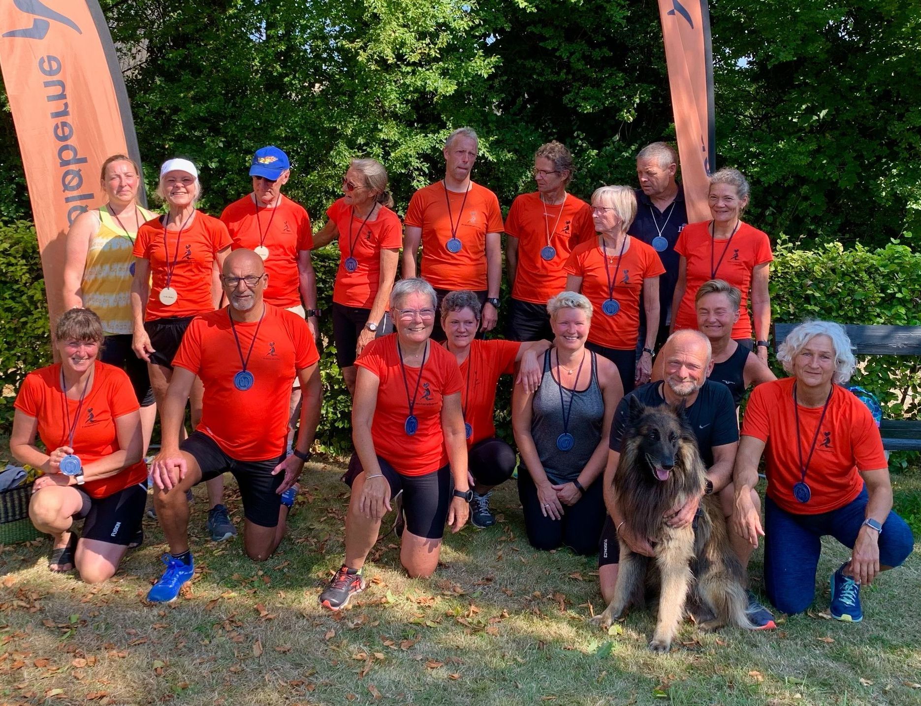 En gruppe mennesker poserer til et billede med en hund.