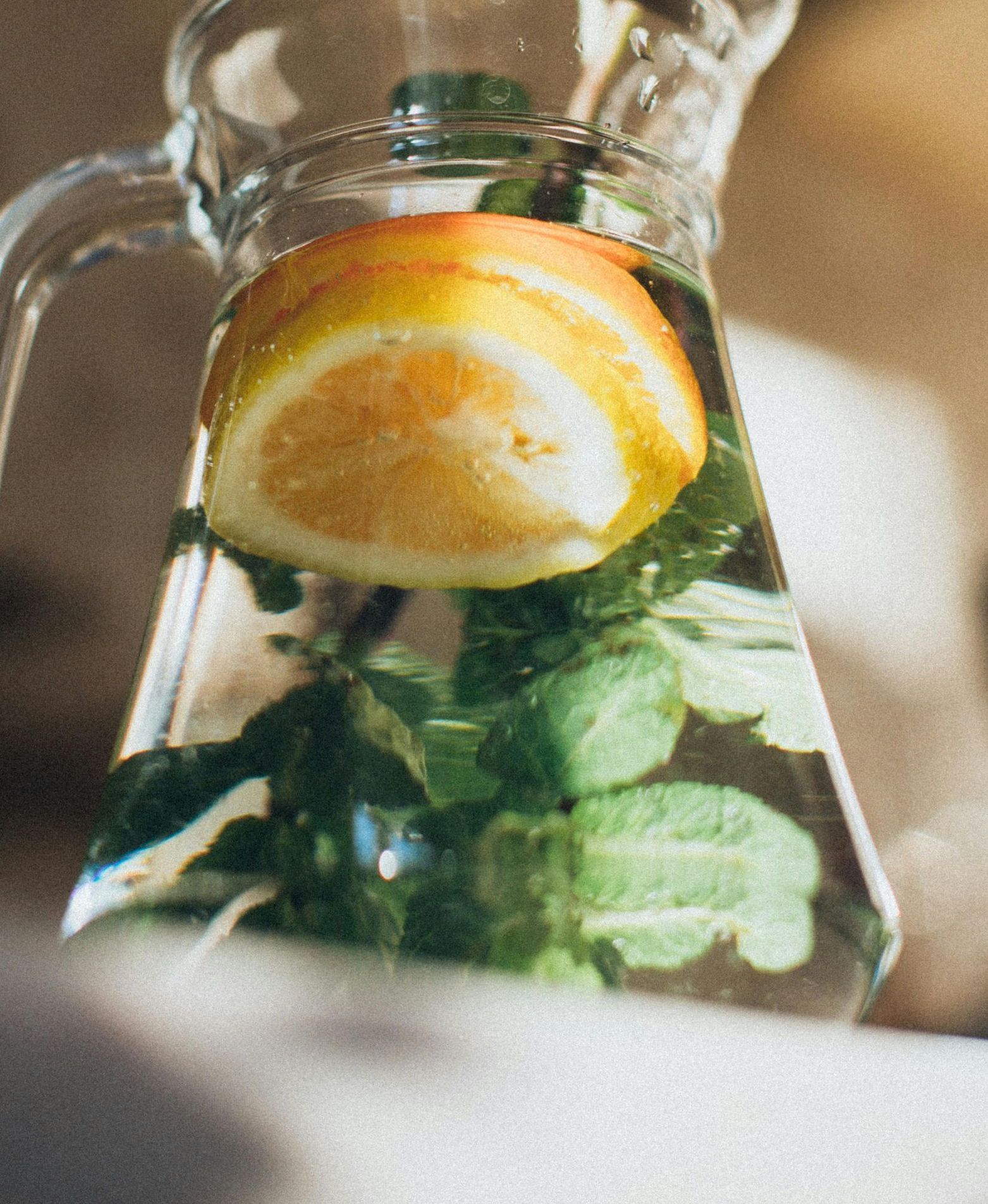 Glass pitcher of water infused with orange slices and mint, a hydration tip from Detoxity Holistic MediSpa in The Woodlands