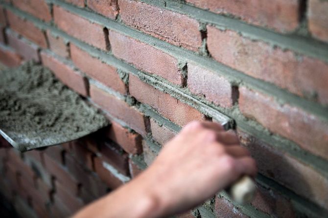 Het met de hand gladstrijken van natte mortel op een bakstenen muur tijdens metselwerkzaamheden.