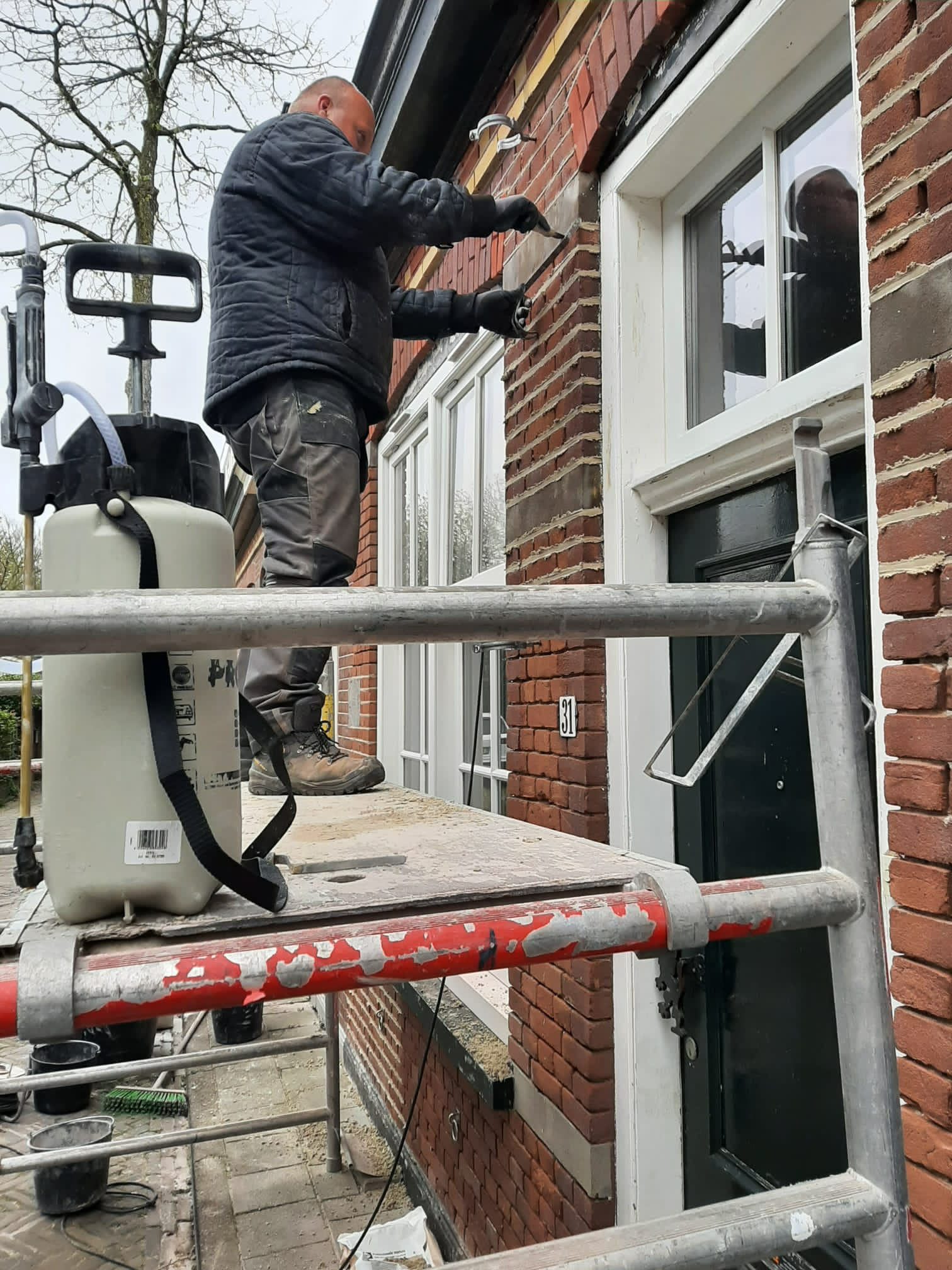 Een werknemer gebruikt een hoogwerker om een ​​raam in een bakstenen gebouw te plaatsen of te repareren.