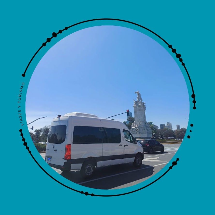 Camioneta blanca estacionada cerca de un alto monumento blanco bajo un cielo azul claro.
