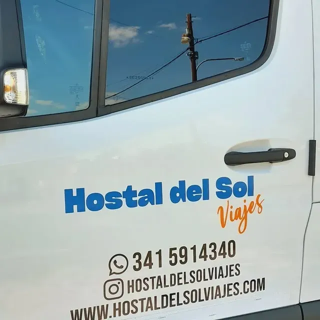 Furgoneta blanca con logo de “Hostal del Sol Viajes” e información de contacto: teléfono, Instagram y sitio web.