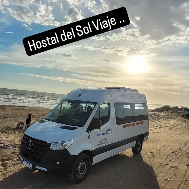 Furgoneta blanca en una playa de arena con el océano al fondo