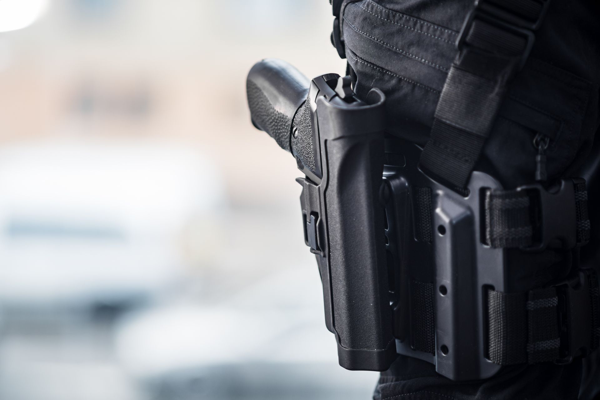 A security guard’s holstered firearm is shown on a duty belt during patrol. A security guard’s holstered firearm is shown on a duty belt during patrol.