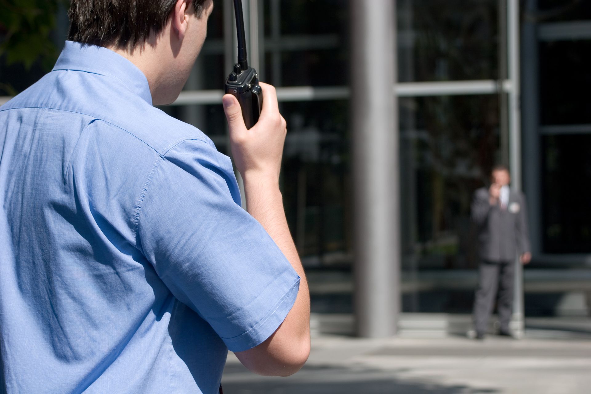 A man in a blue shirt is talking on a walkie talkie