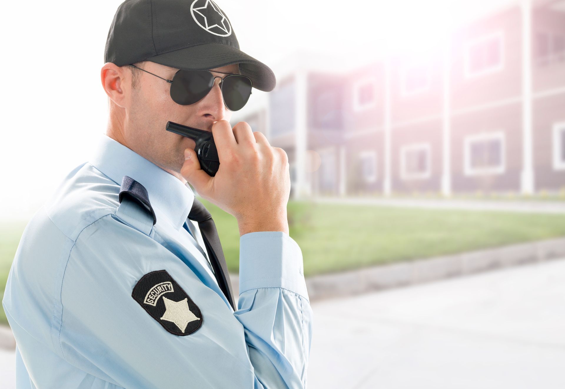 A professional unarmed officer delivering security guard service, using a walkie-talkie outdoors.