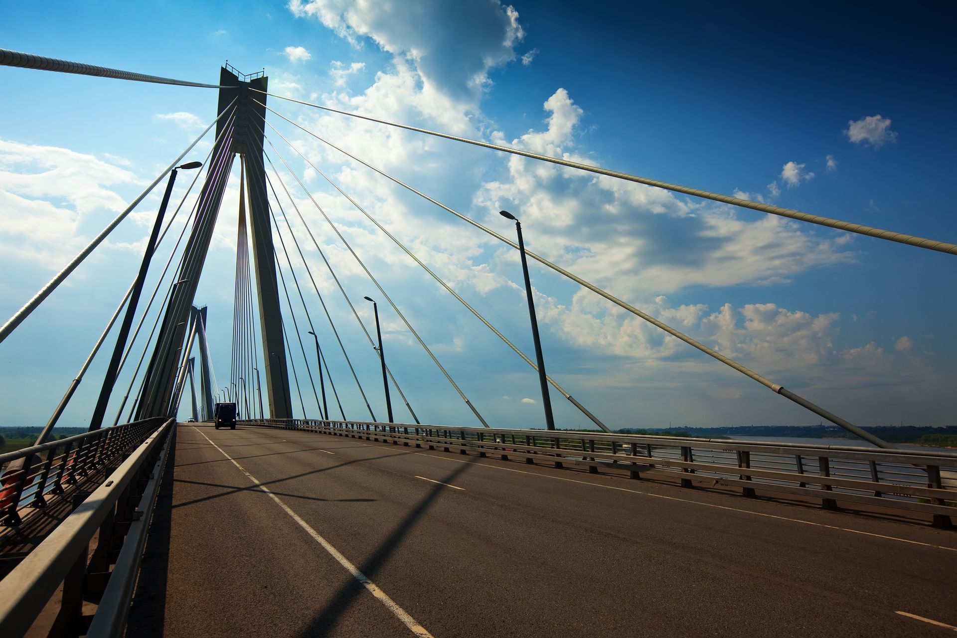 Cable-stayed bridge over a wide roadway under a blue sky with clouds