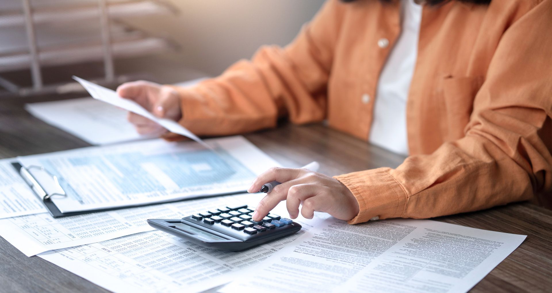 Person using a calculator and reviewing documents for tax planning