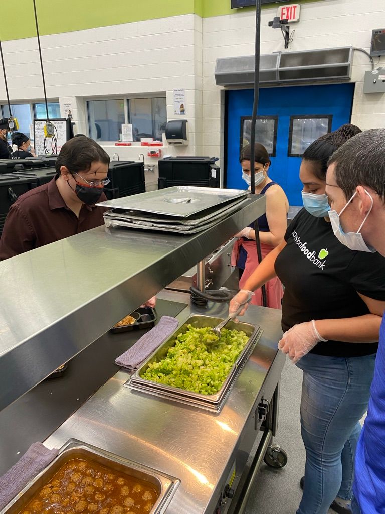 People serving themselves food from a buffet line, including guacamole and chili. Indoor setting.