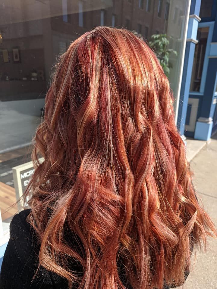 Wavy copper-red hair shown from the back in sunlight near a storefront window