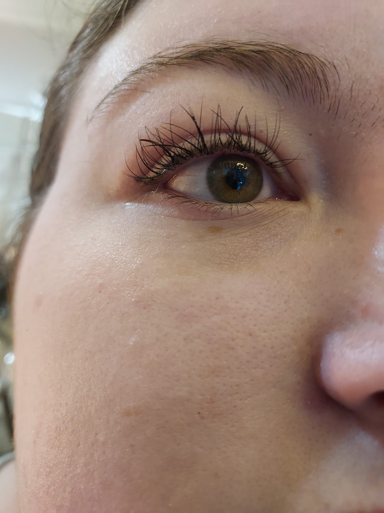 Close-up of a blue eye with long mascara-coated lashes and natural makeup on the cheek and brow
