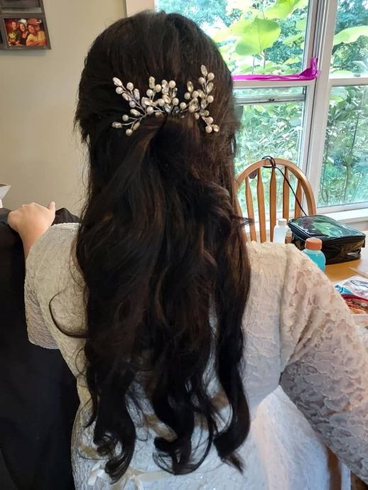 Woman with long dark hair, white lace top, and pearl hair clip, seen from behind in a bright room with a window.