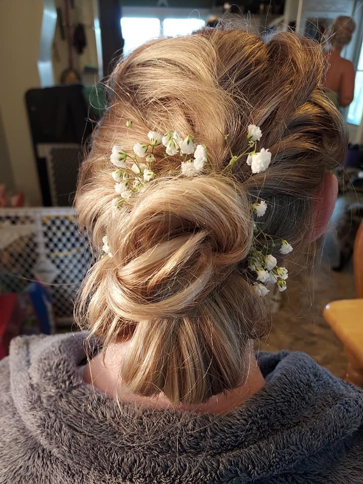 Elegant blonde updo with white flowers, viewed from behind in a salon setting