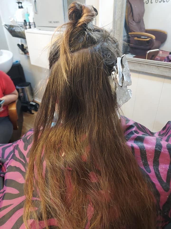 Hair being sectioned with foil at a salon, viewed from behind.