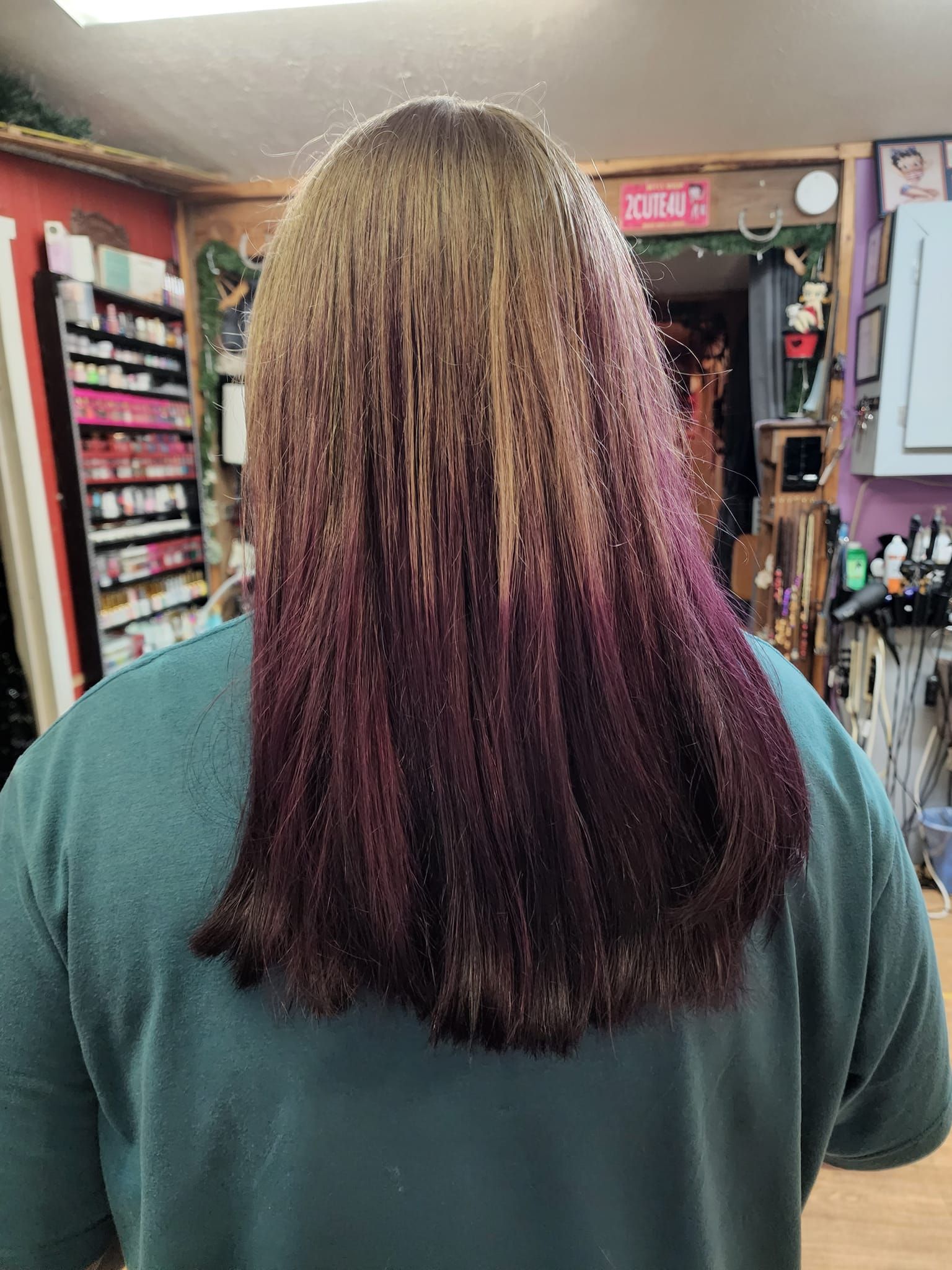 Back view of a person with long braids in a beauty supply store, wearing a green top.