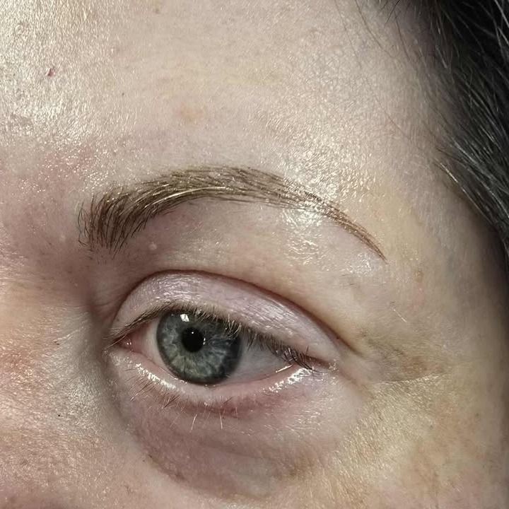 Close-up of a blue-gray eye with a slightly raised brow and minimal makeup