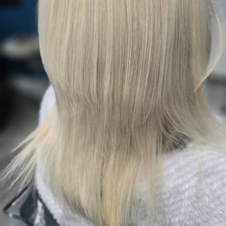 Blonde hair seen from behind, falling over a light gray sweater.