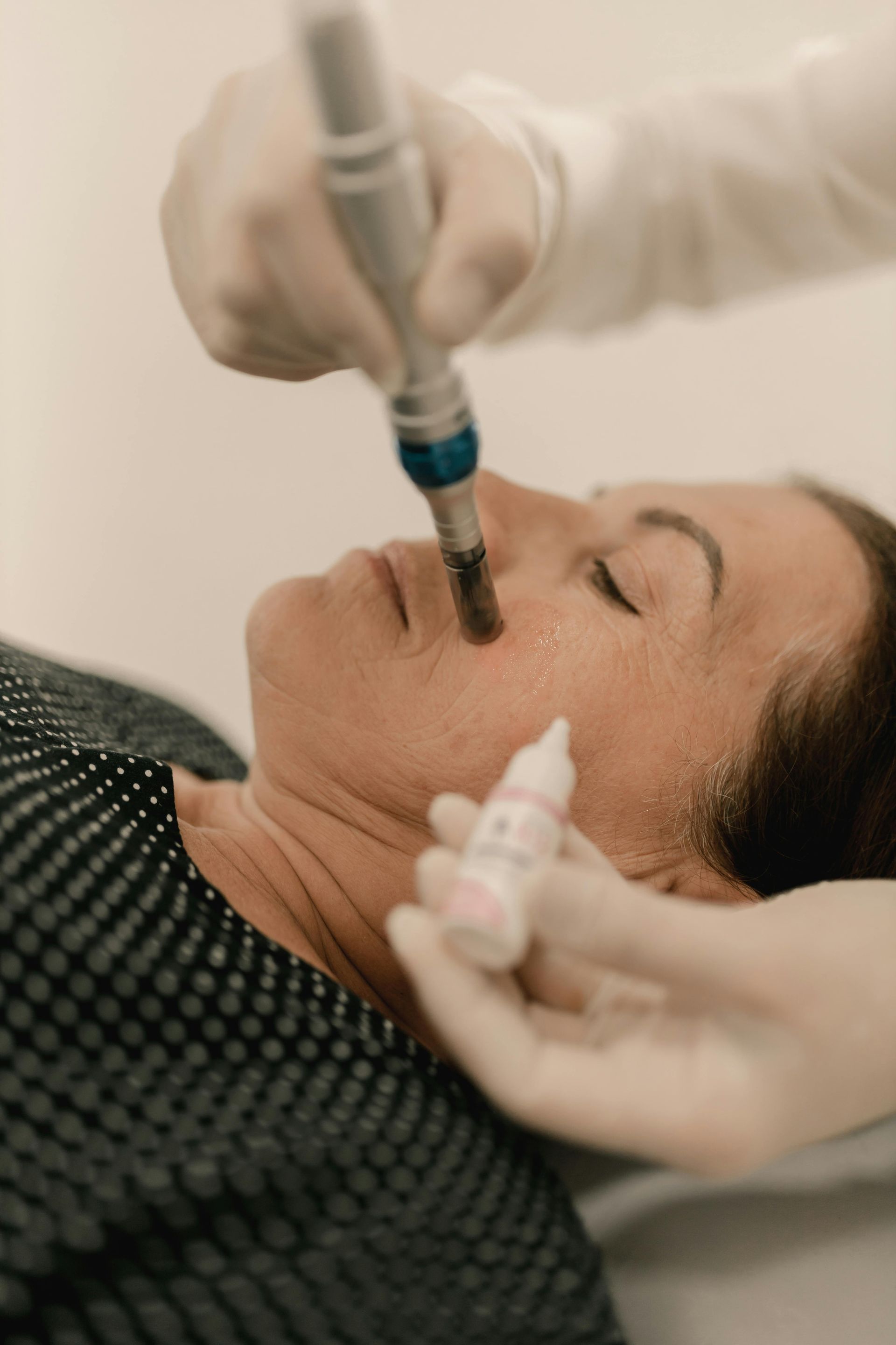 Facial treatment with a cosmetic device applied to a woman's cheek near her eye