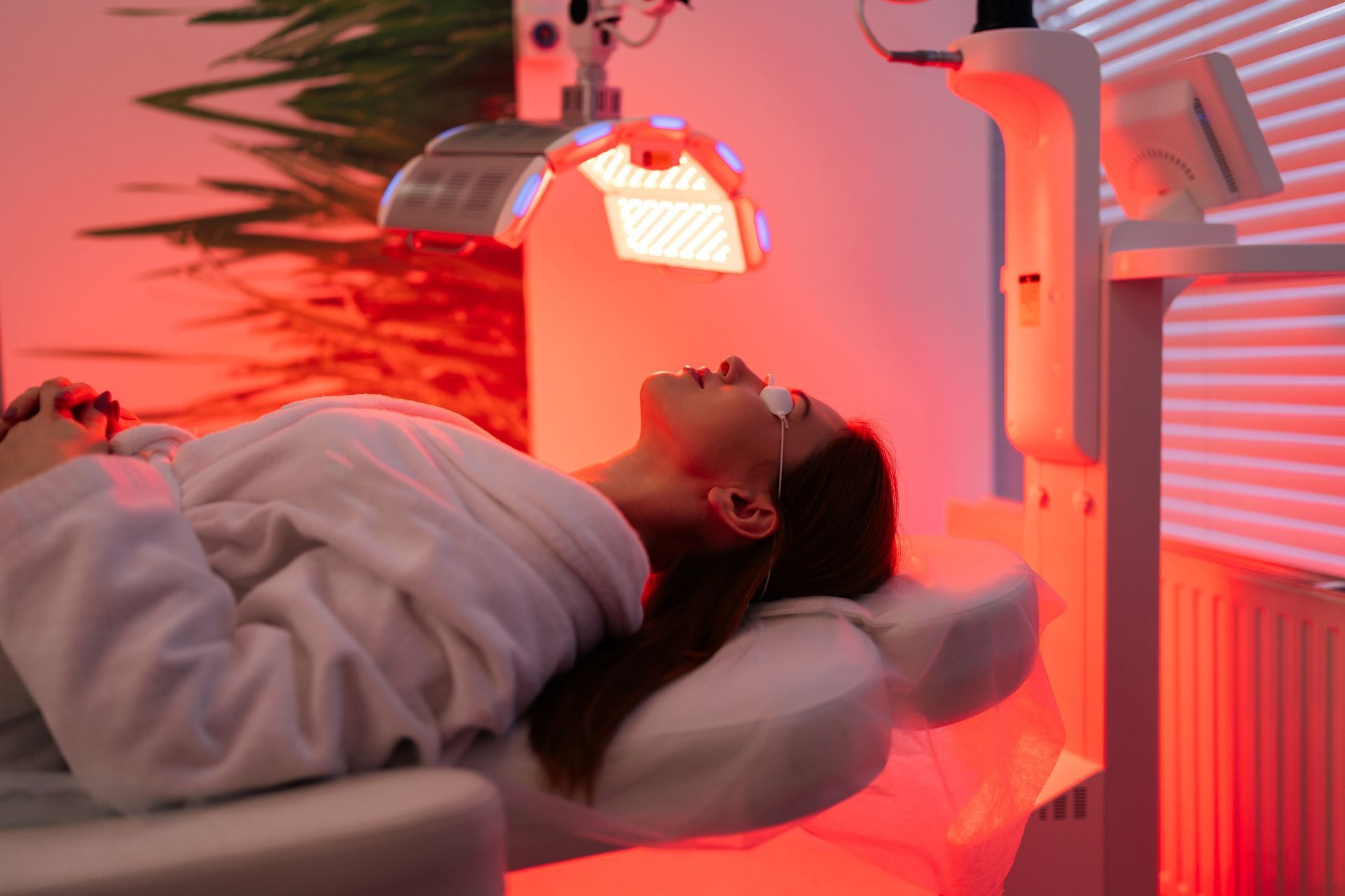 Person lying under a glowing red light therapy lamp in a clinic room