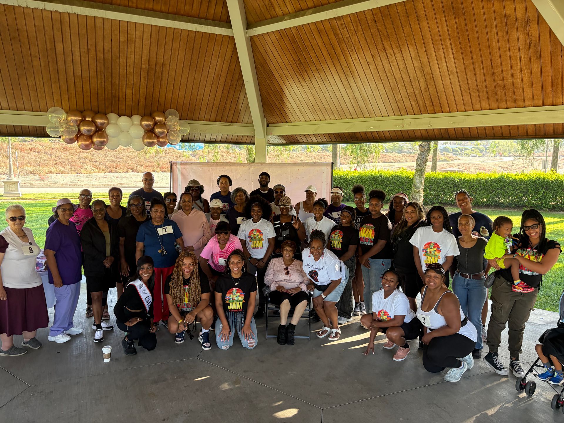 Group of people posing together under a pavilion, with a large whiteboard behind them.