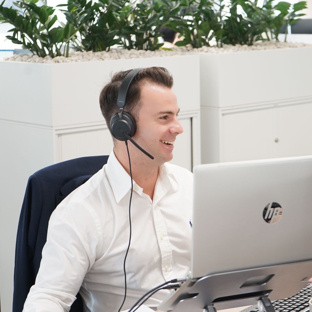 A man wearing headphones is sitting in front of an hp laptop