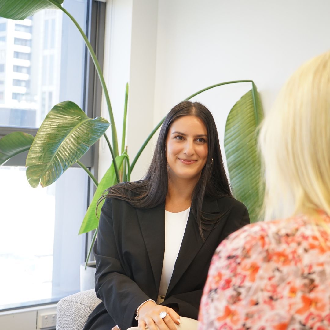A woman in a black jacket is talking to another woman