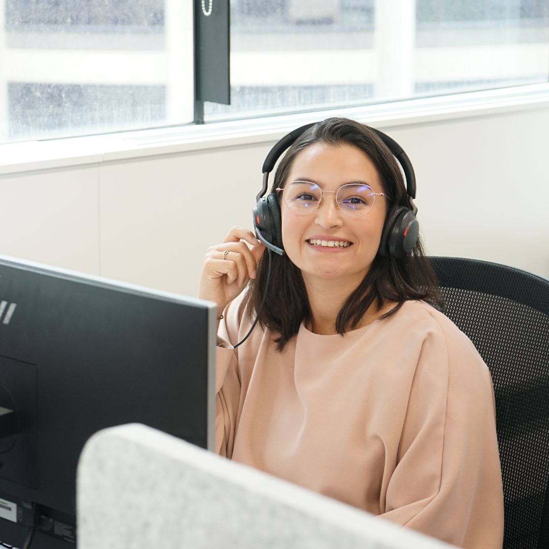 A woman wearing headphones is sitting in front of a computer.