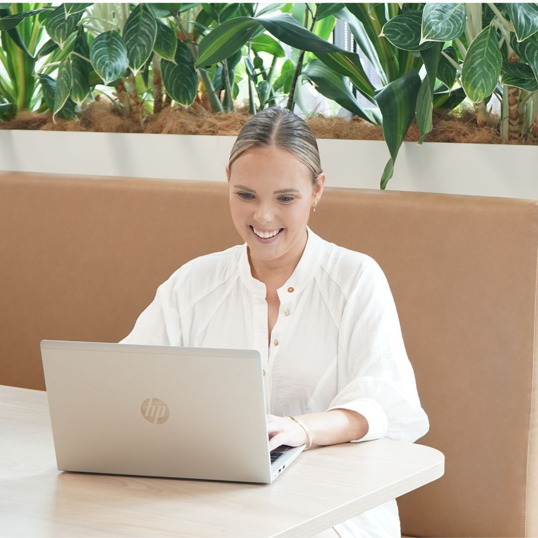 A woman is sitting at a table using an hp laptop