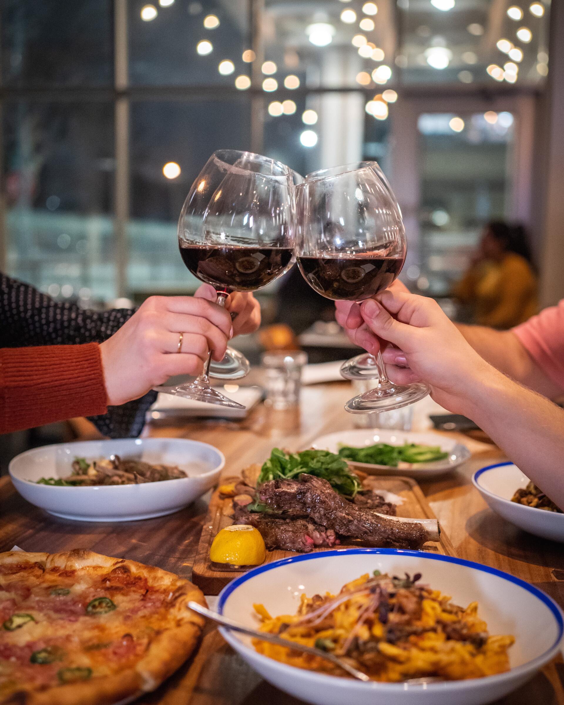 Two people toast their glass of wine