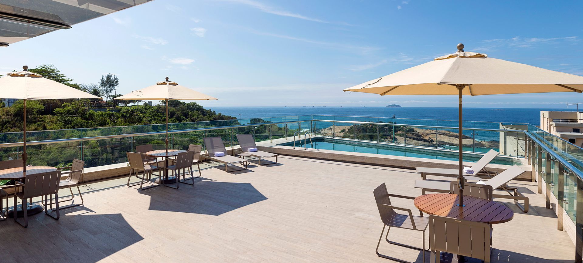 Terraço com vista para o mar, equipado com mesas, guarda-sóis e espreguiçadeiras.