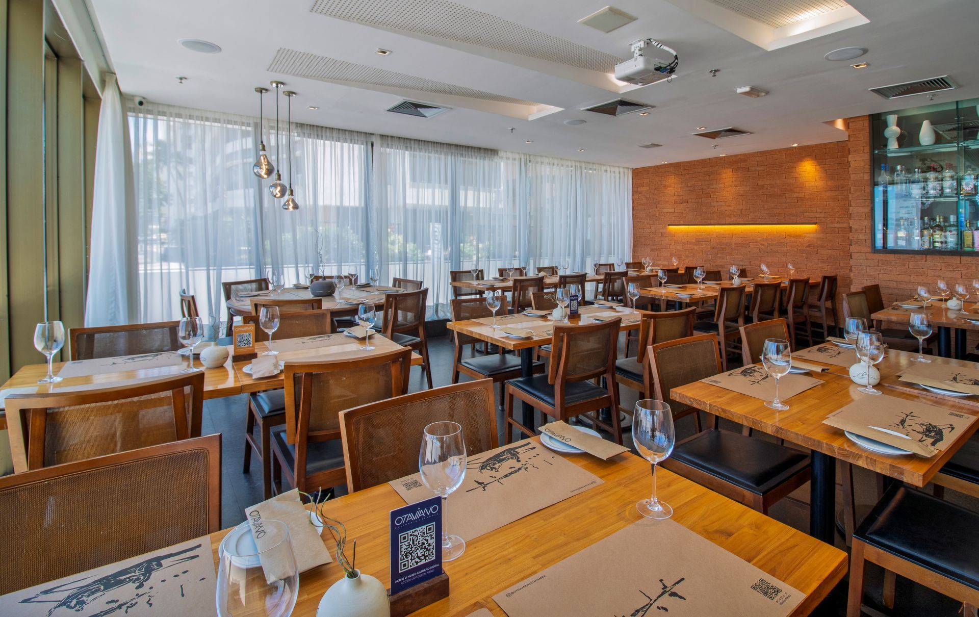 Sala de jantar moderna do restaurante com mesas de madeira, cadeiras de vime e grandes janelas com vista para a água.