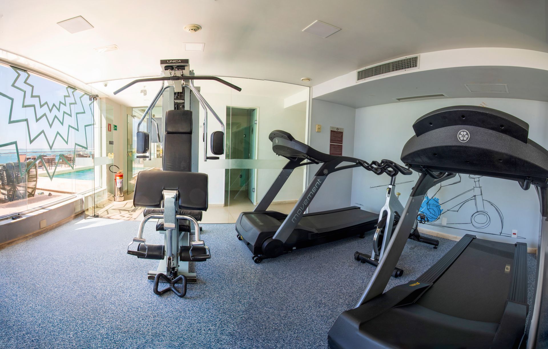 Academia moderna com esteiras, aparelhos de musculação e bicicleta ergométrica em uma sala bem iluminada.