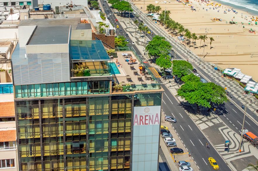 Vista aérea de uma rua litorânea ao lado de um prédio com a placa 