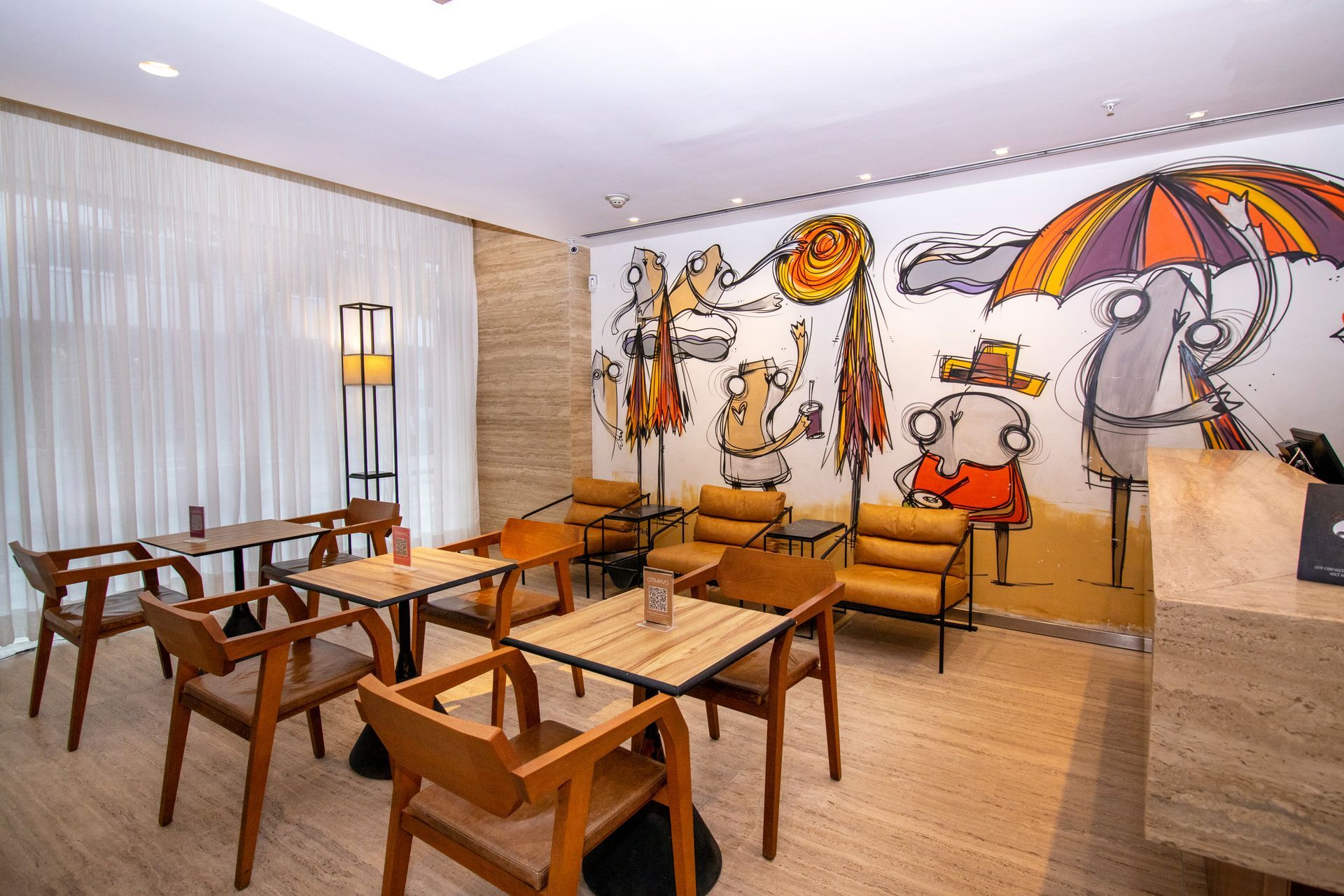 Sala de estar moderna com cadeiras e mesas de madeira, sofás laranja e um mural de animais de desenho animado na parede.