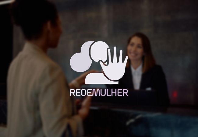 Duas pessoas na recepção com o logotipo da RedeMulher na tela.