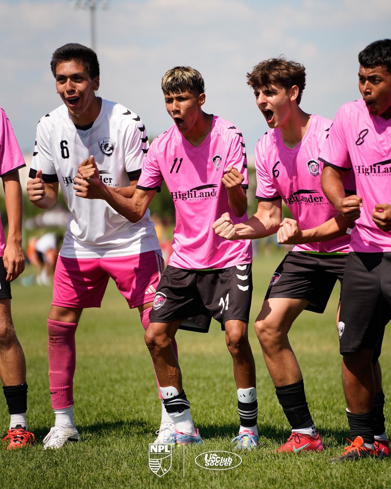 Soccer players in pink and white training tops walk together on a grassy field.