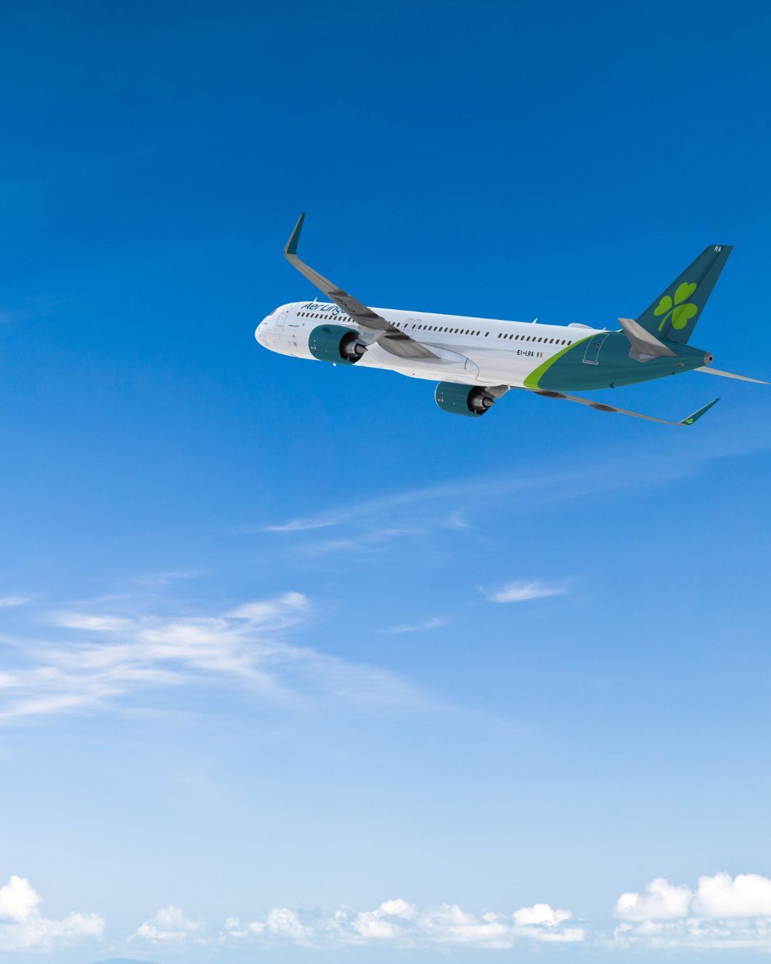 Jetliner flying through a clear blue sky above scattered clouds