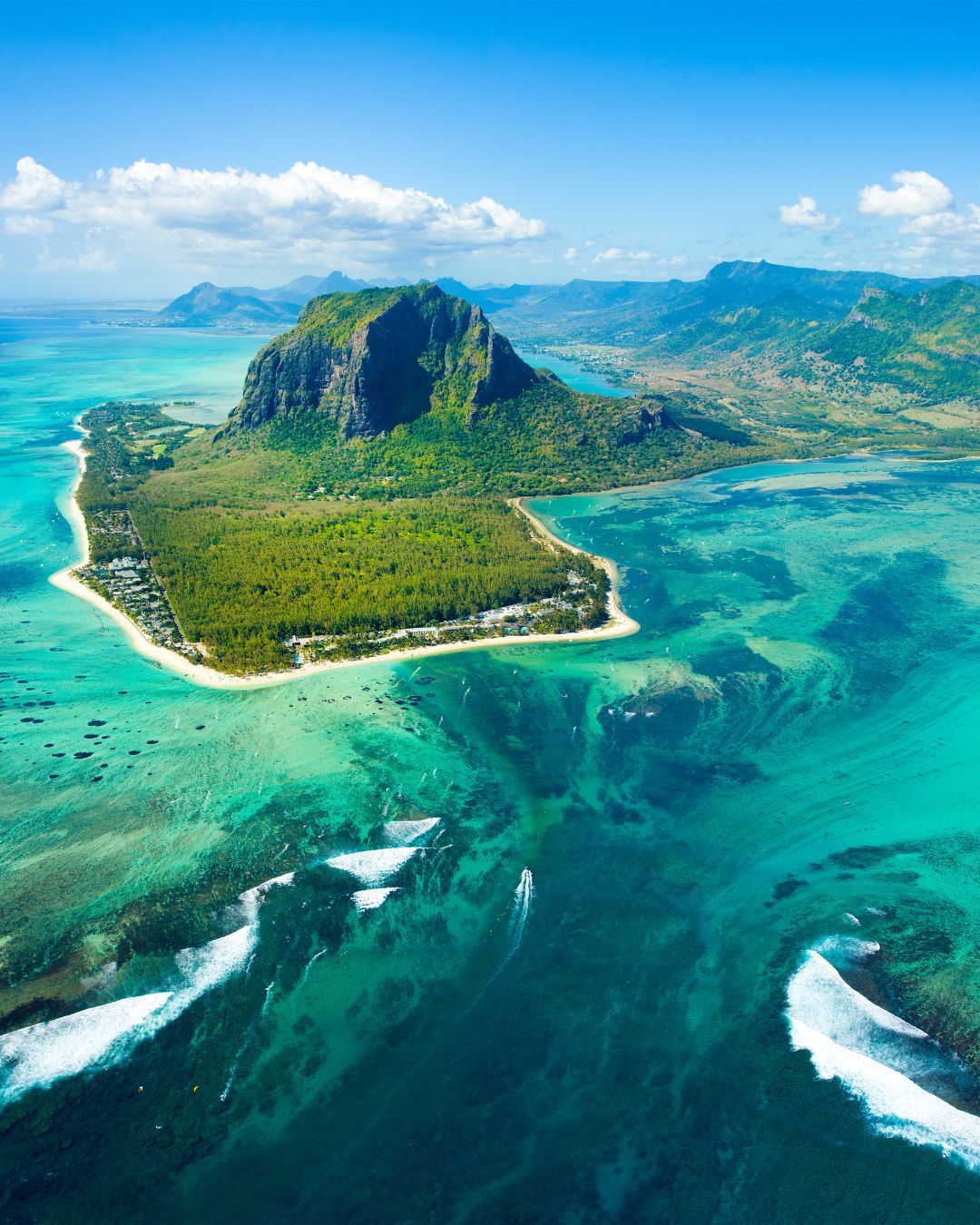 Aerial view of a lush tropical island with turquoise lagoons and white sand beaches.