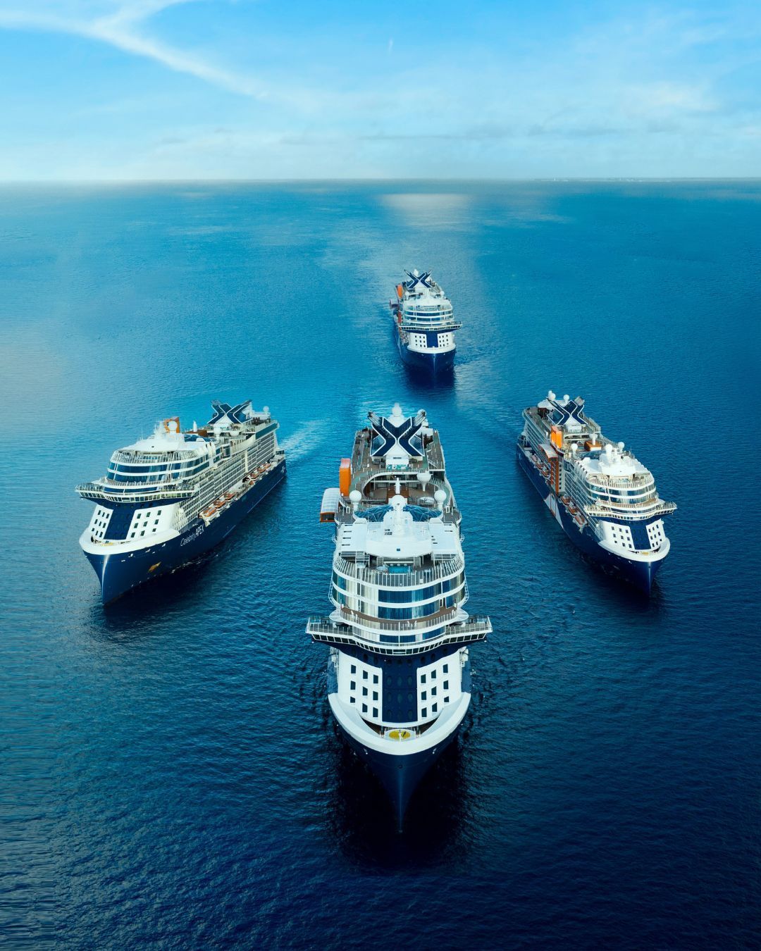 Five cruise ships in formation on a bright blue ocean