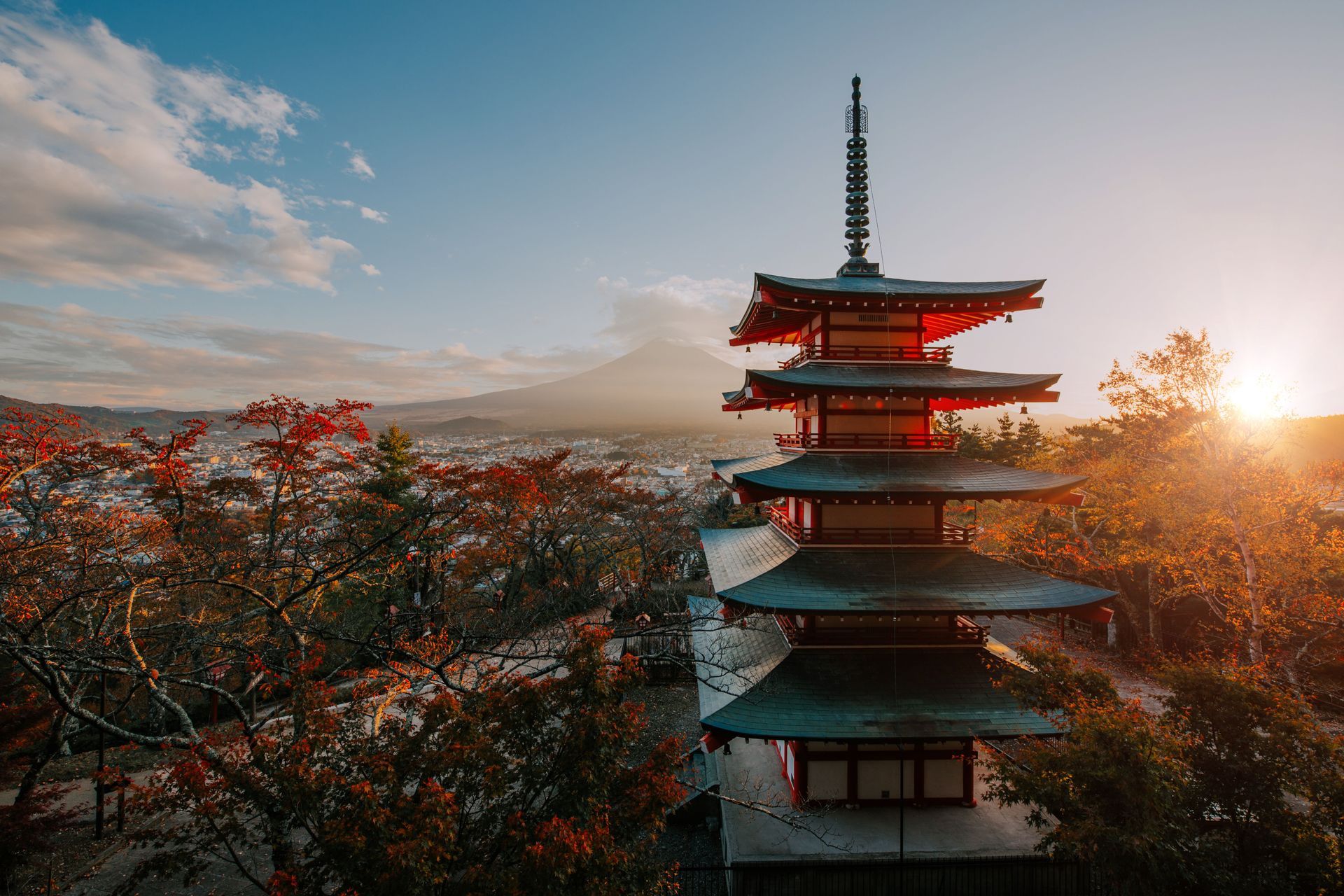 An aerial view of a pagoda with a mountain in the background at sunset.