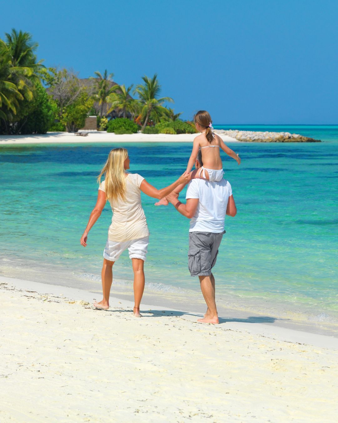 Aerial view of a lush tropical island with turquoise lagoons and white sand beaches.
