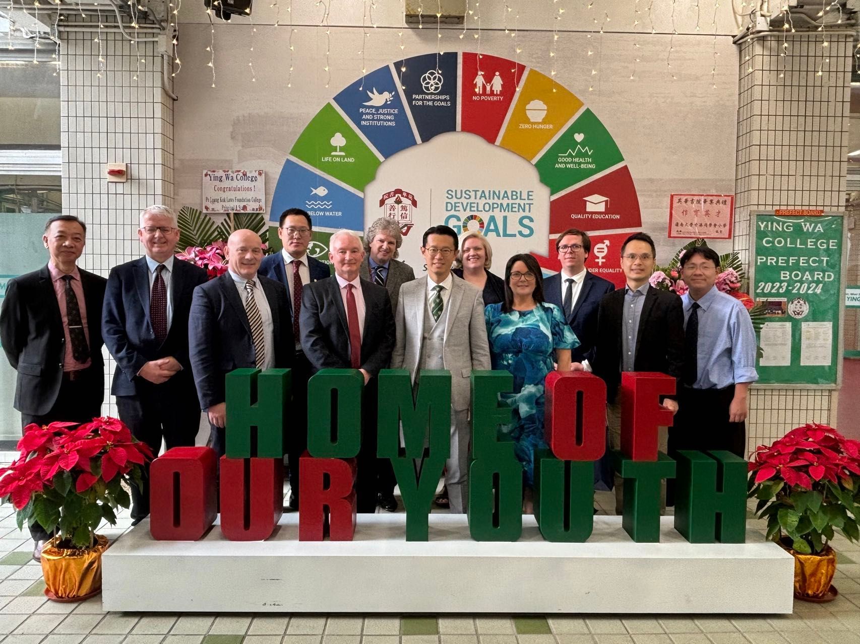 Group of people posing behind a green-and-red “Home of Our Youth” sign at an awards event ICCEC