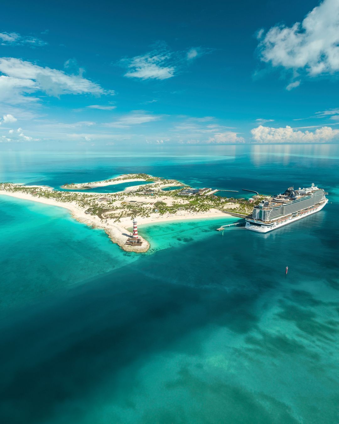 Aerial view of a tropical island resort with turquoise water, white sand, and overwater villas